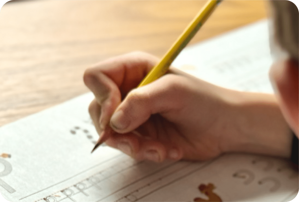 A child practices writing numbers on a worksheet with a pencil, focused and intent.