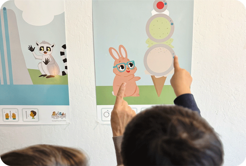 Two children point at a wall poster showing a cartoon rabbit with glasses standing next to a large ice cream cone with three scoops.